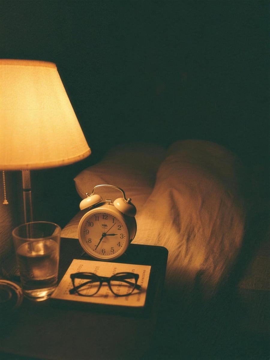 A bedside alarm clock showing a few minutes past three in the morning